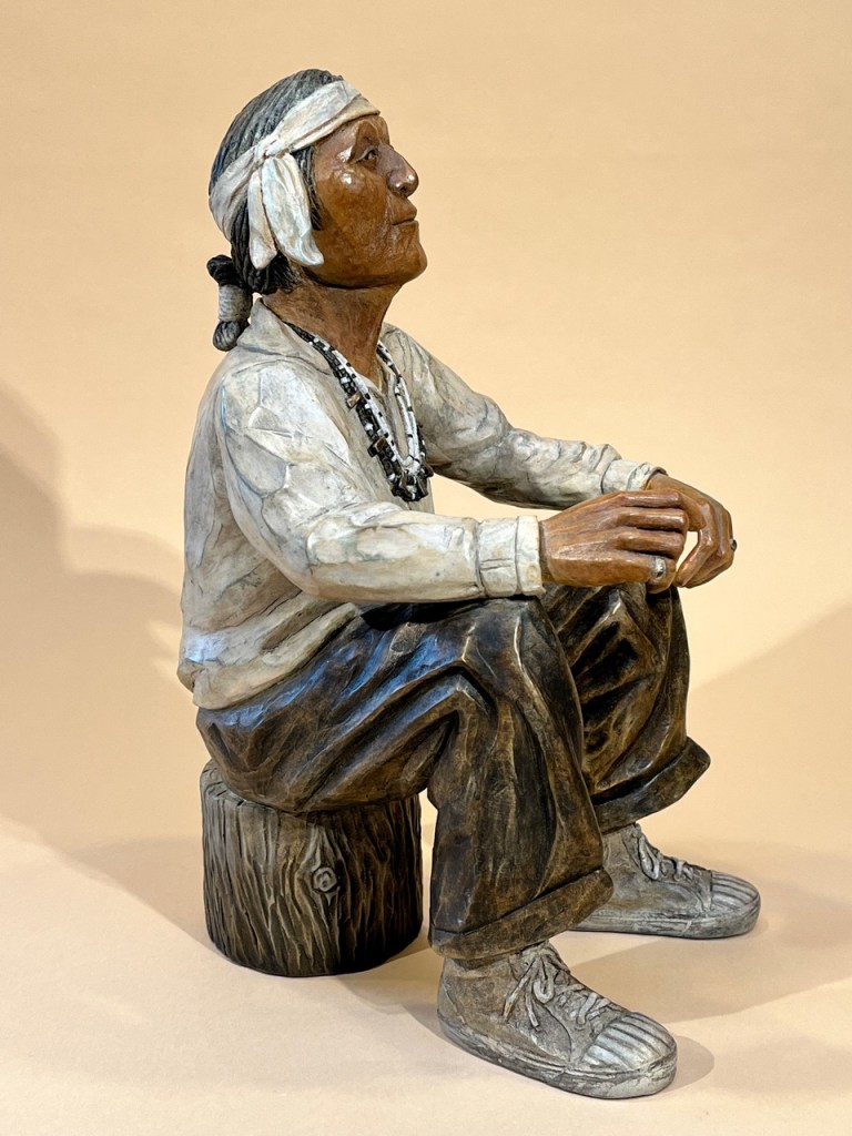 Bronze of a grandfather sitting on a wood stump
