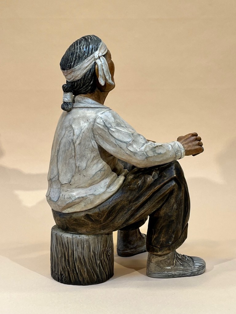 Bronze of a grandfather sitting on a wood stump