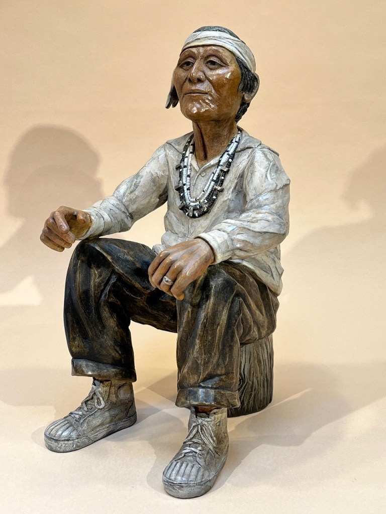 Bronze of a grandfather sitting on a wood stump