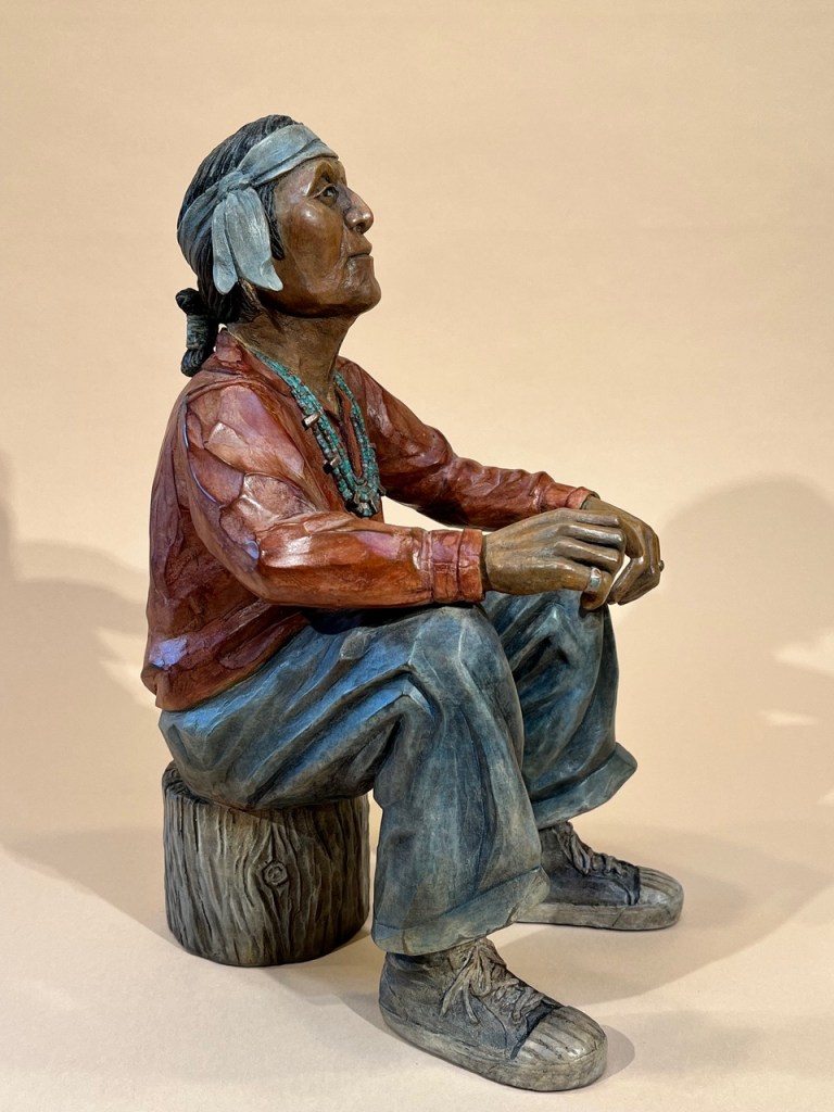 Bronze of a grandfather sitting on a wood stump